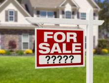 a for sale sign in front of a house.