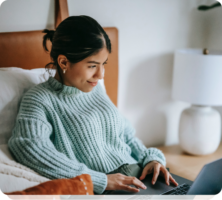 a woman sitting on a bed using a laptop computer